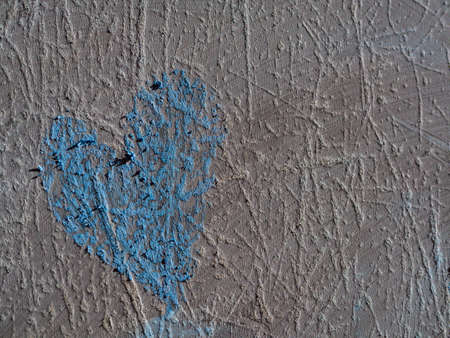 Old black wall, abstract textured background. A blue heart on a scratched gray-black surface. The surface is an old blackboard close-up.の写真素材