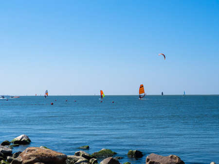 Summer holidays on the beach. Focus on the foreground. A walk on the sea on a board with a sail. windsurfing and kitesurfing. beautiful summer seascape.の写真素材