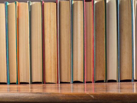 A row of old hardcover books. Books on a wooden shelf, turned back cover. Books from the Home Library.の写真素材