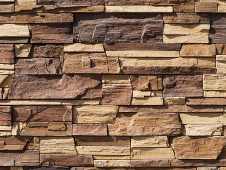 Abstract background of masonry walls made of stones. Brown stone wall close-up. Facing with a stone...