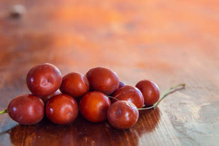 Ripe juicy unabi berries (ziziphus) close-up on a wooden surface. Shiny orange-red fruit jujubeの写真素材