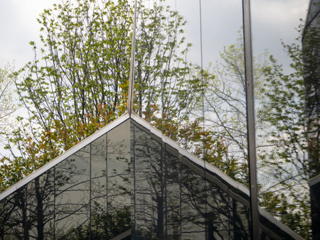 Re-reflections on the polished stone black surface of a modern structure. Trees, the sky and part of...