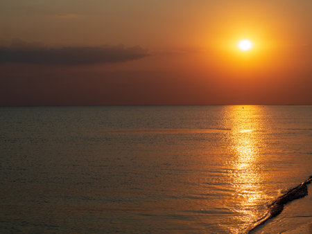 Sunset on the beach overlooking the sea and the sun. Orange sunset and a sunny path on the surface of the water. colorful sea sunsetの写真素材