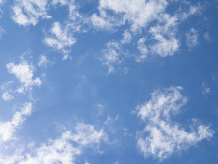 Blue sky and light white clouds illuminated by light on a sunny day. Amazing sky background for design or wallpaperの写真素材