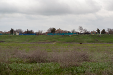 Rural landscape. Village houses on a high bank near pastures with green and dry grass meadowsの写真素材