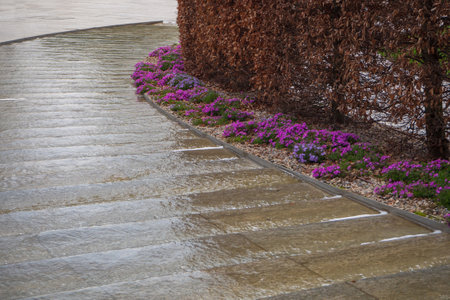Water flows down the decorative stone steps of the path in the city park in early spring. Part of Landscape Designの写真素材