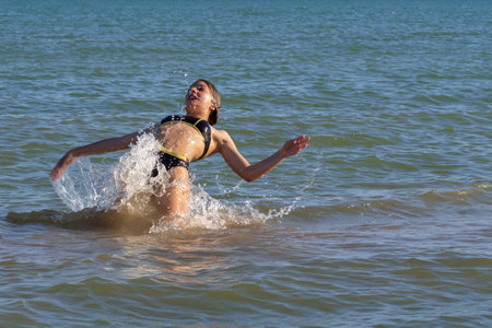 A happy girl is swimming in the sea. girl jumping in seawaterの写真素材