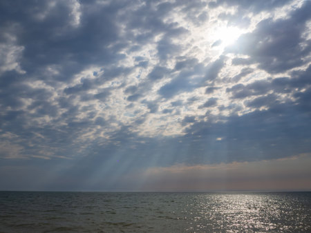 Heavenly sun rays through cumulus clouds over the seaの写真素材