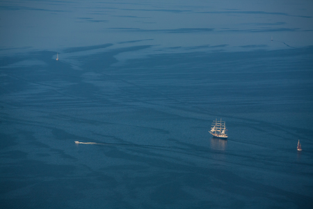 View from above. Several yachts and sailboats go to sea under sail.