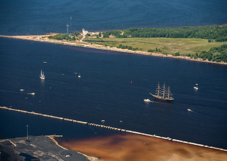 Sailboats and yachts go to sea. A pier at the mouth of the river. Daugava. Bolderaja lighthouse and...
