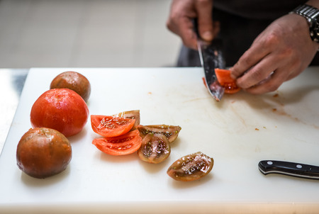 Chef. A restaurant. Cutting tomatoes with a kitchen knife.の写真素材