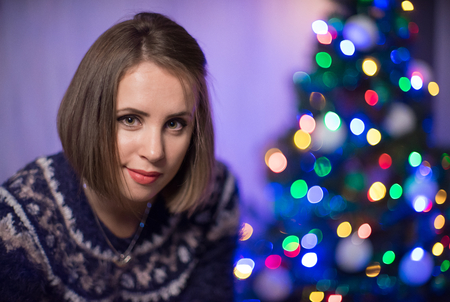 A portrait of girl with christmas tree on the background.の写真素材