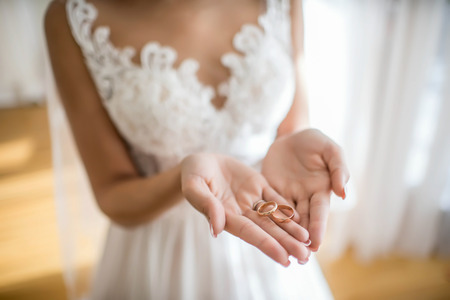 The bride holds in hands golden wedding ringsの写真素材