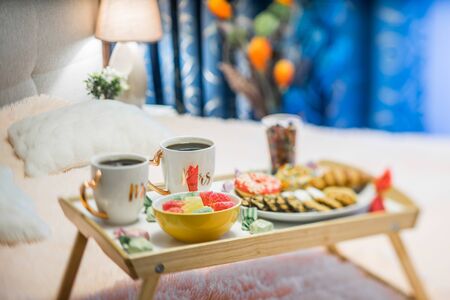 Tray with cookies, marmalade and donuts. One focused cup.