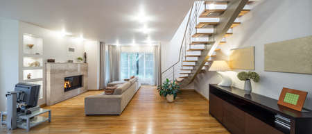 Beautiful living room with fireplace. Stairs to up. Panorama windows.の写真素材