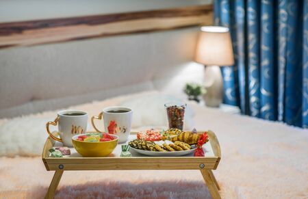 Tray with cookies, marmalade and donuts. A pair of full cups.