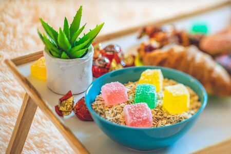 The bowl of cereal with colorful marmalade. Sweets, flower and pastry.