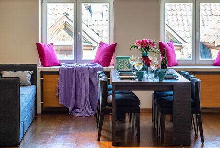 View on the served table in studio apartment. Big windows.