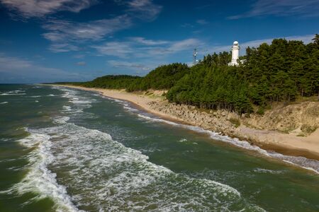 White Uzhava lighthouse on the shore of Baltic Sea. Sunny day.の写真素材