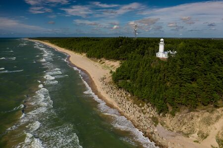 White Uzhava lighthouse on the shore of Baltic Sea. Sunny day.の写真素材