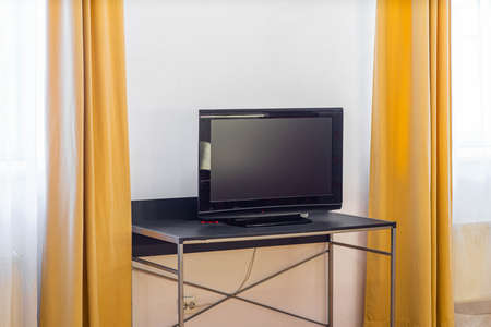 Turned off TV on the stand in modern simple interior of living room. Close-up.