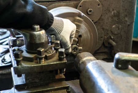 Close-up of hand in glove and lathe. Thread cutting on a stud. Metalwork equipment.
