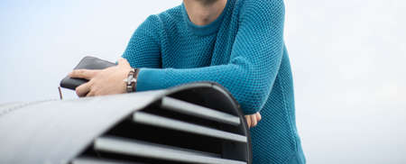 A man in a blue knitted sweater. Shoulders and arms.