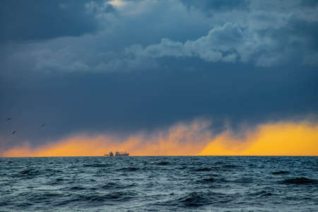 Dramatic sunset over Baltic sea. Ships in the distance. Cloudy sky.