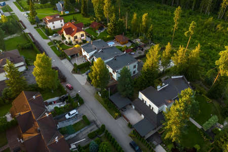 Top drone view of luxury cottage village near green forest. Modern architecture. Private sector.