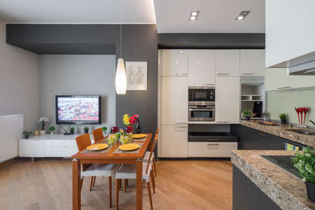 Modern interior of kitchen in studio apartment. TV on the wall. Private house.