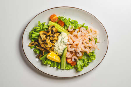 Close-up of delicious food isolated on white. Prawns, fried mushrooms and greens with sauce.の写真素材