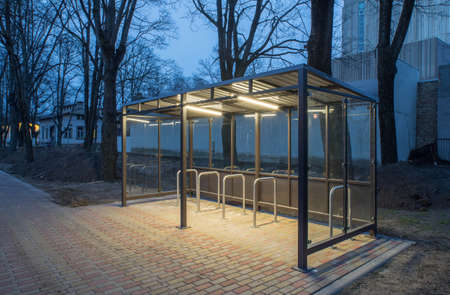 Modern parking space for bicycles, equipped with lighting. Evening time.