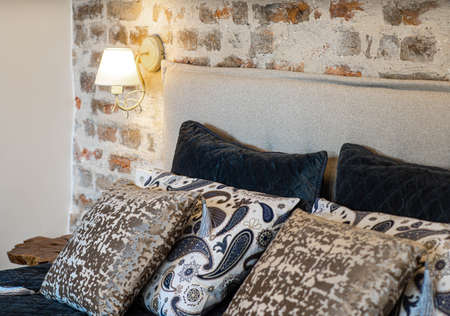 Close-up of cozy bed with pillows. Modern loft interior of bedroom. Lamp on the brick wall.の写真素材