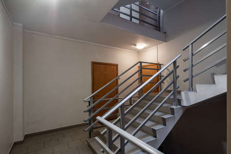 Interior of entrance in modern residential complex. Staircase. Block of flats. Wooden doors.