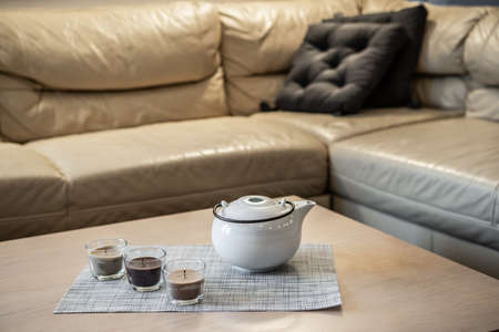 Close-up of teapot and candles on coffee table near cozy couch. Modern interior of living room.の写真素材