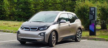 Electric car parked near charging station. Caring for environment.