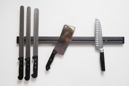Magnetic holder with set of knives on white wall.の写真素材