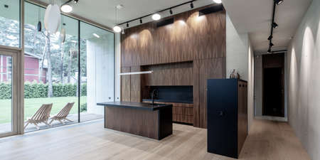 Modern interior of wooden kitchen in luxury private house. Garden view.