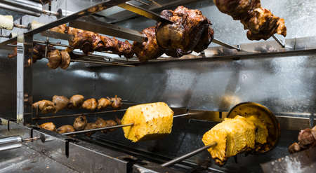 Pineapples and different meats are cooked on electric grill.の写真素材