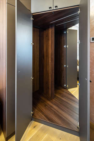 Opened empty wooden wardrobe with mirror inside. Furniture in bedroom.の写真素材