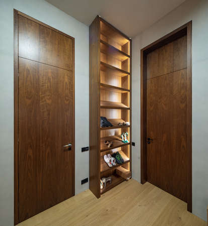 Modern interior. Illuminated wooden shelves for shoes.