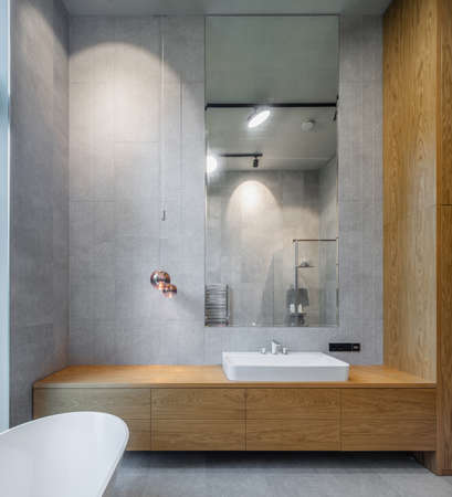 Interior of bathroom in luxury flat. Grey and wooden design. White sink.の写真素材