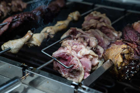 Different meats are cooked on skewers on electric grill in restaurant.の写真素材