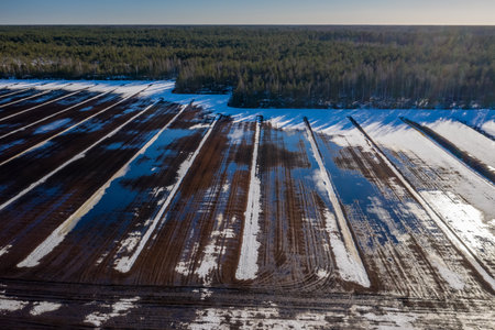 Early spring. Sunny day. Aerial view. Field with snow and puddles.の写真素材