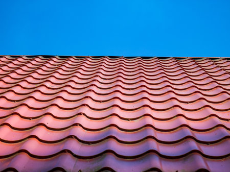 Red clay ceramic tiled roof. Blue sky. Close-up.の写真素材