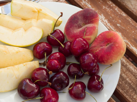 Fresh cherry, peaches and pieces of apple and pear on plate. Close-up. Healthy food.の写真素材