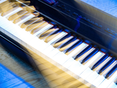 Fragment of musical instrument. White and black piano keys. Electronic synthesizer. Blue light. Motion blur.の写真素材