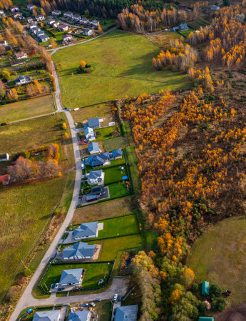 Aerial drone view of small cottage village. Luxury private houses near road. Green field, autumn forest. Sunny day.の写真素材