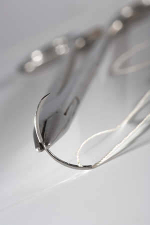The old holder  with a surgical needle and silk  On a white background 