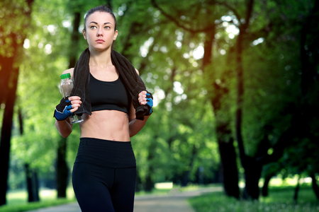 Young beautiful and strong woman resting after an active workout at the summer park. Sports concept. Healthy lifestyleの写真素材